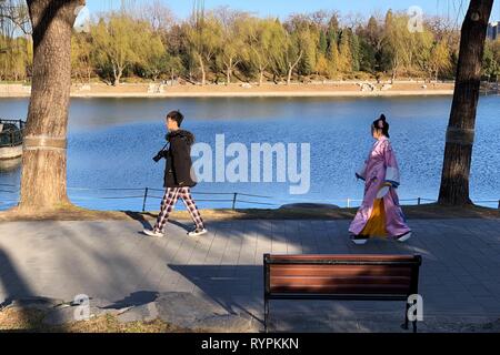Pechino, Cina. Xii Mar, 2019. Foto scattate con un telefono cellulare mostra una donna in costume a piedi dopo un fotografo nel Parco Taoranting a Pechino Capitale della Cina, 12 marzo 2019. Credito: Zhang Haofu/Xinhua/Alamy Live News Foto Stock