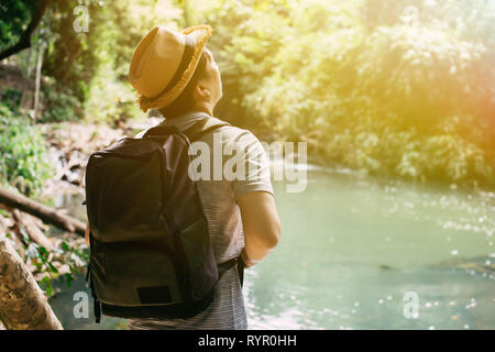 Retro del giovane maschio asiatica travel backpacker con hat e zaino in viaggio nella foresta verde giungla per lo stile di vita di avventura. Foto Stock