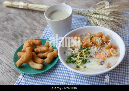 Breakfase pasto. Congee o riso porridge di carne macinata di maiale, uovo sodo con latte di soia e il cinese fritte doppio bastone di pasta Foto Stock