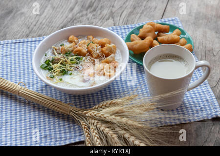 Breakfase pasto. Congee o riso porridge di carne macinata di maiale, uovo sodo con latte di soia e il cinese fritte doppio bastone di pasta Foto Stock