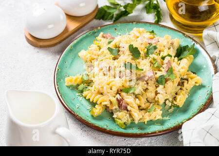 La pasta alla carbonara con zucchine nel mestiere la piastra sul bianco. Foto Stock