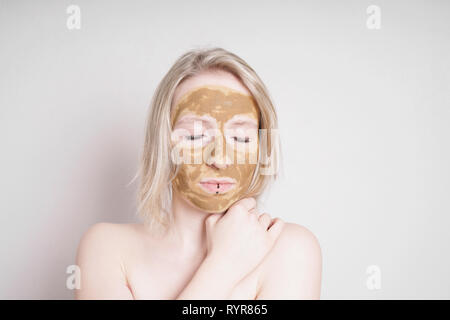 giovane donna con terra curativa o maschera facciale di bellezza in argilla godendo di un trattamento di benessere Foto Stock