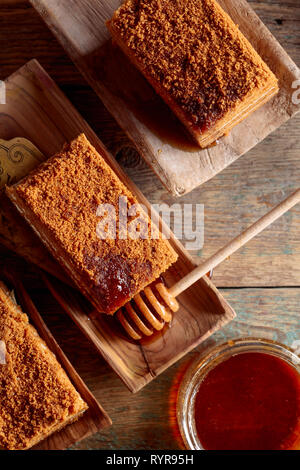 Torta di miele e un vaso di miele su un vecchio tavolo di legno. La vista dall'alto. Foto Stock