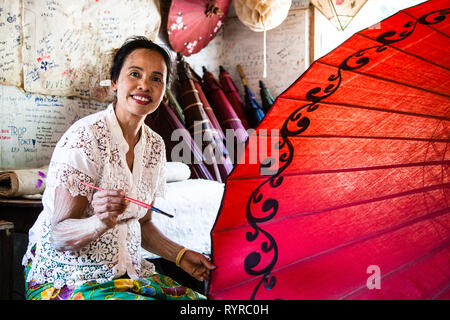 Una donna rende la carta ombrelloni a un ombrello workshop in Pindaya, Myanmar Foto Stock