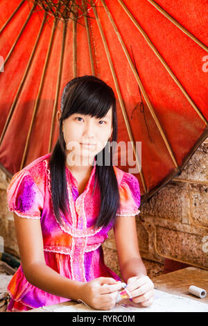 Una donna rende la carta ombrelloni a un ombrello workshop in Pindaya, Myanmar Foto Stock