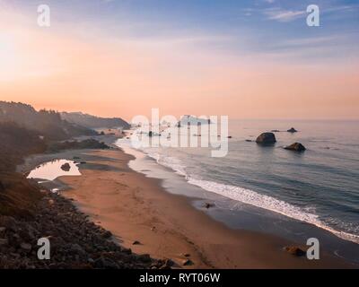 Sunrise, spiaggia sabbiosa, il paesaggio costiero con molte rocce frastagliate isole, Oregon, Stati Uniti d'America Foto Stock