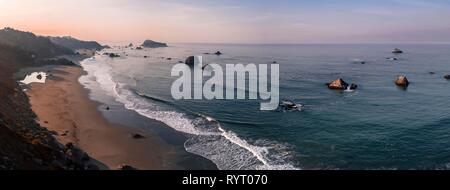 Sunrise, spiaggia sabbiosa, il paesaggio costiero con molte rocce frastagliate isole, Oregon, Stati Uniti d'America Foto Stock