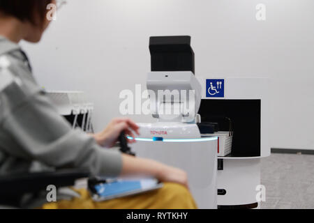 Tokyo, Giappone. Xv Mar, 2019. Sostegno umano Robot prende le merci ad un personale in sedia a rotelle dalla consegna robot di supporto a Tokyo in Giappone, il 15 marzo 2019. Entrambi i robot possono essere utilizzati in Tokyo 2020 Giochi Olimpici e Paraolimpici. La Tokyo 2020 Comitato Organizzatore ha annunciato il lancio della sua nuova Tokyo 2020 Progetto di robot il venerdì. Credito: Du Natalino/Xinhua/Alamy Live News Foto Stock