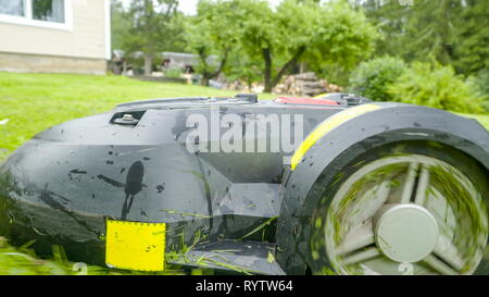 Il lato della striscia gialla automower in esecuzione in avanti sul prato verde della casa Foto Stock