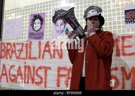 Una donna visto che parla rivolgendosi agli assistenti durante la Veglia in memoria di un attivista brasiliana Marielle Franco. I dimostranti si sono riuniti al di fuori dell'ambasciata brasiliana a Londra per onorare la vita e l eredità di attivista brasiliana Marielle Franco che era apertamente critico nei confronti della brutalità della polizia e le uccisioni extragiudiziali contro favela residenti. Franco è stato assassinato per la sua attività politica insieme con il suo autista Anderson Gomes su Marzo 14, 2018 a Rio de Janeiro in Brasile. Durante la veglia ha affrontato gli assistenti e rivendicato giustizia e hanno chiesto la fine dell'impunità in Franco cri Foto Stock