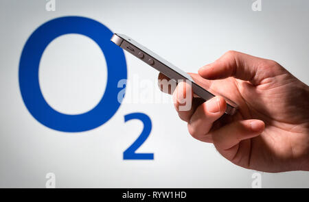 Un uomo con un telefono cellulare nella parte anteriore di un O2 segno Foto Stock