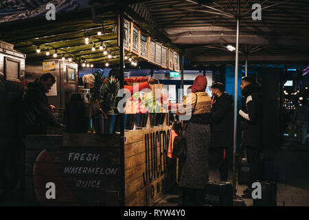 London, Regno Unito - 9 Marzo 2019: persone che acquistano frutta e succhi di frutta freschi da Juicebox stallo in Oxford Street, Londra, la sera. Oxford street si trova a uno o Foto Stock