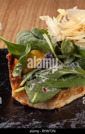 Insalata verde con fette di carne pancetta croccante pane arrostito tomatoe insalata di cavolo mais formaggio uovo di pollo formaggio tagliati servita nel cestello sul tavolo Foto Stock