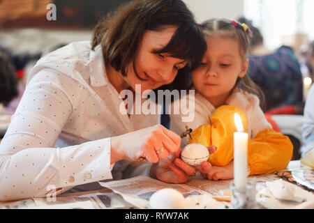 Lviv, Ucraina - 11 Marzo 2018. Mamma e figlia dipingere le uova di Pasqua a tavola Foto Stock