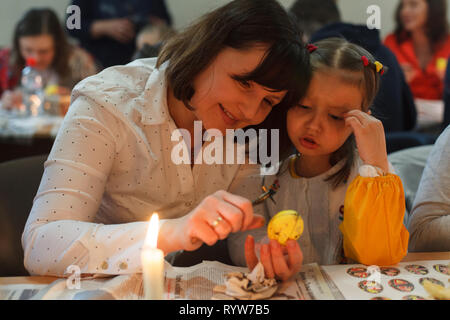 Lviv, Ucraina - 11 Marzo 2018. Mamma e figlia dipingere le uova di Pasqua a tavola Foto Stock