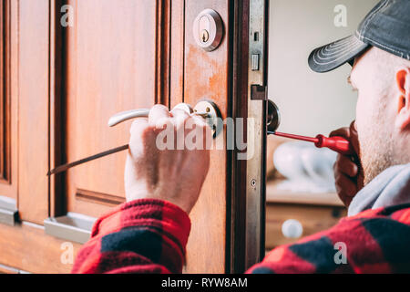 Fabbro avvitamento in una nuova serratura della porta e la maniglia Foto Stock