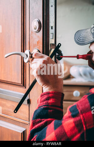 Fabbro preciso cambia la serratura di una porta Foto Stock