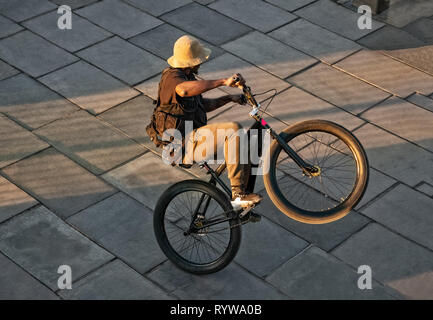Giovane uomo in sella a una moto su facendo pedonale acrobatici volteggi nella luce del tramonto in Trafalgar Square di Londra Foto Stock
