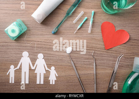 Concetto di famiglia assicurazione dentaria con elementi rappresentativi e strumenti per via orale su un marrone tavolo in legno. Composizione orizzontale. Vista superiore Foto Stock