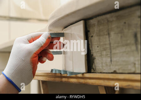 Del lavoratore i sostegni a mano piastrella sulla parete curva utilizzando cunei in plastica. Foto Stock