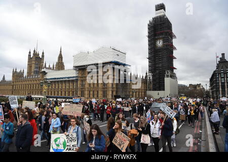 Gli studenti marzo passato Case del Parlamento durante la scuola globale sciopero per il cambiamento climatico a Londra, come le proteste sono pianificati in 100 paesi e città nel Regno Unito. Foto Stock