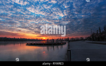 In inverno il paesaggio luminoso sul lago ghiacciato in Kriviy Rih, Ucraina. Bella Nuvoloso Tramonto nel parco. Vista dei resti all'interno della città Foto Stock