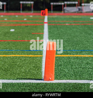 Un tappeto erboso verde campi da calcio linea di traguardo è contrassegnato con piloni arancione , una linea bianca e un segnale di colore arancione con una G su di esso. Foto Stock