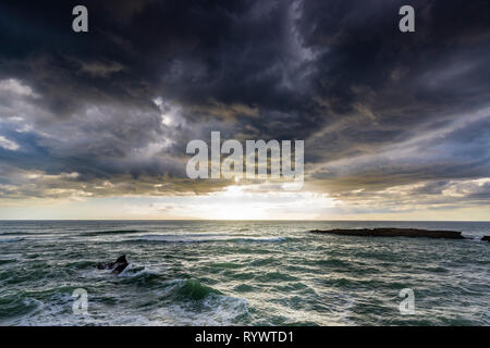 Ruvida, il mare in tempesta con spray bianco e la nebbia, Tramonto throught majestetic nuvole a Kere Kere Beach, Nuova Zelanda, Northland Foto Stock