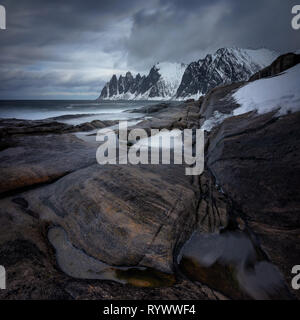 Tugeneset costa rocciosa con le montagne sullo sfondo, Norvegia Foto Stock