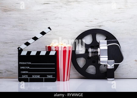 Close-up di un Movie Camera con popcorn e battaglio Scheda contro uno sfondo bianco Foto Stock