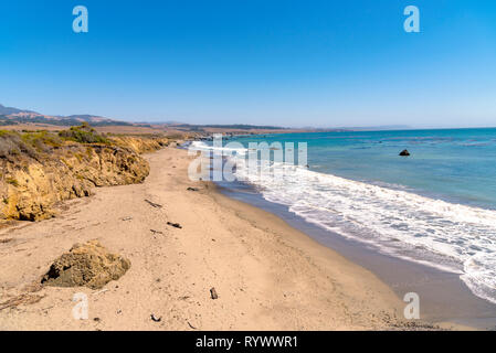 Mare blu con onde il rotolamento su spiagge di sabbia sotto il cielo limpido. Foto Stock