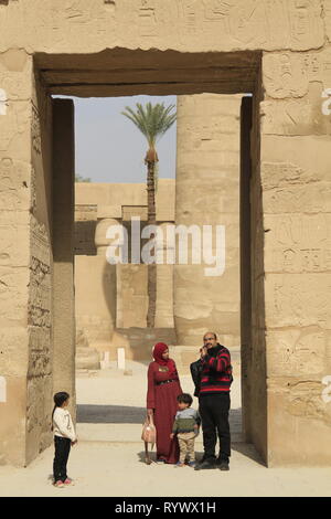 Famiglia di visitatori, donna in hijab, in piedi in una grande entrata di pietra modo, Distretto di Amon-Ra, Tempio di Karnak complessa, Luxor, Egitto Foto Stock