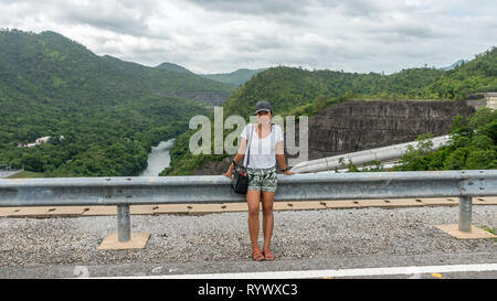 Donna asiatica seduto sul guard rail in Thailandia con il fiume in background Foto Stock