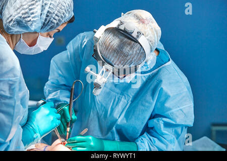 Il team di chirurghi fa un intervento invasivo. Ritratto di chirurghi di close-up. Lavorare con uno strumento di coagulazione, coagulazione vascolare Foto Stock