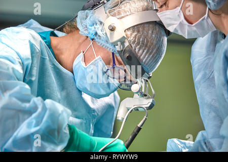 Il team di chirurghi fa un intervento invasivo. Ritratto di chirurghi di close-up. Lavorare con uno strumento di coagulazione, coagulazione vascolare Foto Stock