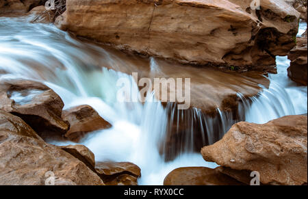 L'acqua che scorre e cascata attraverso una pietra arenaria slot canyon. Silky effetto dell'acqua con un flusso di acqua blu. Foto Stock