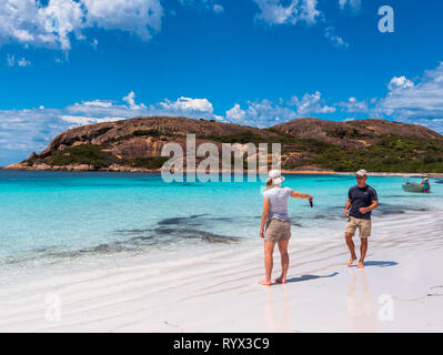 Lucky Beach, Esperance, Australia -- il 9 febbraio 2018. Una donna è di consegnare un telefono cellulare al suo compagno come egli cammina verso di lei su incredibilmente beaut Foto Stock