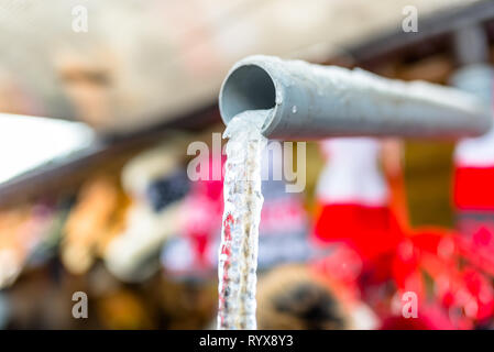 Acqua congelata che fluisce dal tetto attraverso un tubo in plastica con una stringa all'interno. Foto Stock