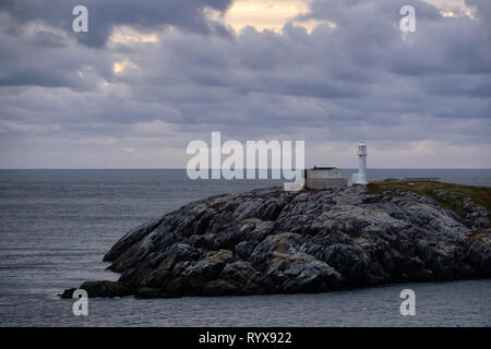 Faro sul roccioso Oceano Atlantico costa durante un NUVOLOSO TRAMONTO. Preso in Channel-Port aux Basques, Terranova, Canada. Foto Stock