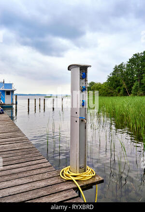 Stazione di ricarica per barche e prese di corrente per il carico delle navi nel porto. Punto Bollard delle prese elettriche sul molo presso il lago Schwerin. Foto Stock