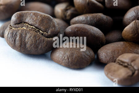 Primo piano di una pila di chicchi di caffè con sfondo bianco in basso a destra Foto Stock