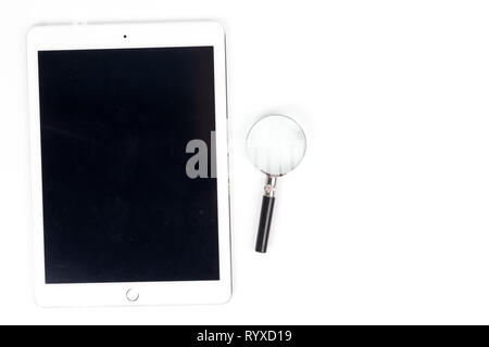 Area di lavoro vista superiore la compressa,lente di ingrandimento è collocato su una scrivania bianca nel concetto di ufficio Foto Stock