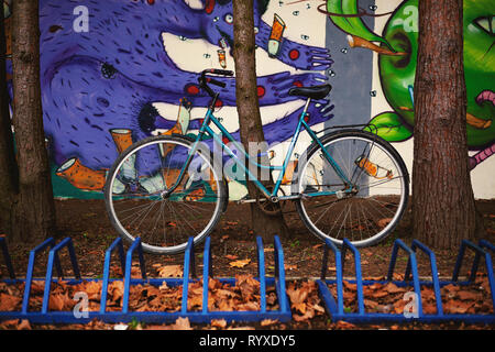 Cacak, Serbia - Marzo 14, 2019: vecchie biciclette blu parcheggiato e bloccata ad albero, graffiti sulle pareti, stile di vita normale i dettagli. Foto Stock