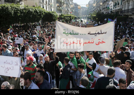 Algeri, Algeria. Xv Mar, 2019. Persone marzo con bandiere e cartelli durante una manifestazione di protesta contro il Presidente Abdelaziz Bouteflika per la decisione di ritirarsi da e a rinviare le elezioni presidenziali dell'aprile 2019, oltre ad annunciare un non meglio specificato periodo transitorio, un passo visto dai manifestanti come un tentativo di prolungare la sua regola. Credito: Farouk Batiche/dpa/Alamy Live News Foto Stock