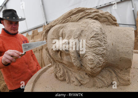 Binz, Germania. Xii Mar, 2019. Il lituano scultore Donatus Mockus sta lavorando sulla scultura di sabbia "Klaus Störtebeker' sui terreni della scultura di sabbia festival. Artisti provenienti da vari paesi europei stanno attualmente creando 45 cifre enormi per il decimo la scultura di sabbia Show nel Mar Baltico località balneare di Binz. La scultura di sabbia mostra apre il 16.03.2018. Credito: Stefan Sauer/dpa-Zentralbild/dpa/Alamy Live News Foto Stock