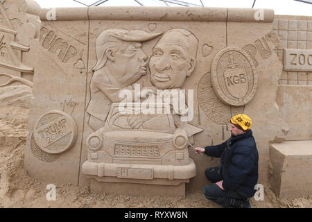 Binz, Germania. Xii Mar, 2019. Lo scultore Wlodek Bludnik dalla Polonia sta lavorando sulla scultura di sabbia "Muro di Berlino" con una versione moderna del graffito del fratello bacio sulla motivazione della scultura di sabbia Festival. Essa ci mostra il presidente Donald Trump e il Presidente russo Vladimir Putin. Artisti provenienti da vari paesi europei stanno attualmente creando 45 cifre enormi per il decimo la scultura di sabbia Show nel Mar Baltico località balneare di Binz. La scultura di sabbia mostra apre il 16.03.2018. Credito: Stefan Sauer/dpa-Zentralbild/dpa/Alamy Live News Foto Stock