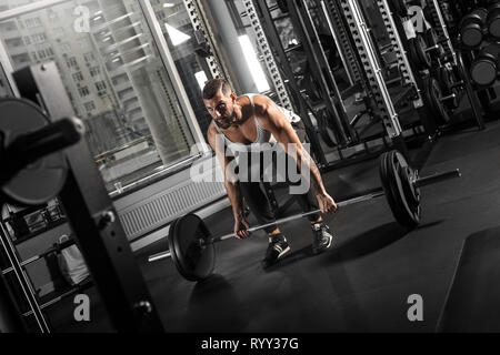 Bodybuilding. Uomo Barbuto esercizi in palestra chinarsi con barbell concentrata vista laterale Foto Stock