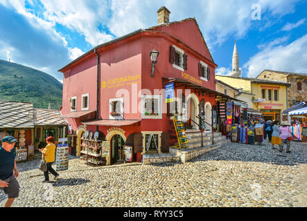 I turisti negozio per regali e souvenir e vagare Mostar Bosnia città vecchia con un minareto in background Foto Stock