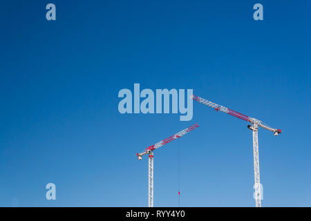 A causa delle gru contro il cielo blu chiaro Foto Stock