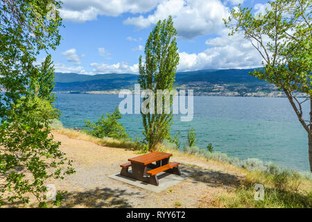 Tavolo da picnic e panchine sulla riva del lago Okanagan. Foto Stock